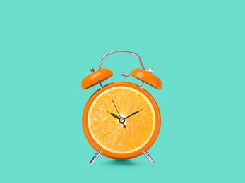 Image of Juicy orange on alarm clock dial against turquoise background. Creative poster