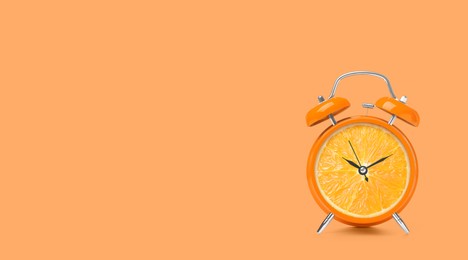 Image of Juicy orange on alarm clock dial against light coral background. Creative poster with space for text, banner design