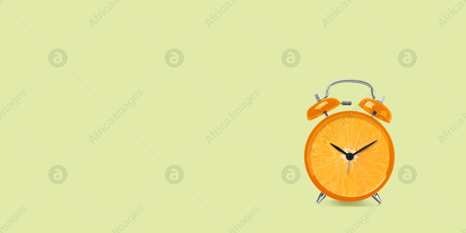 Image of Juicy orange on alarm clock dial against light green background. Creative poster with space for text, banner design