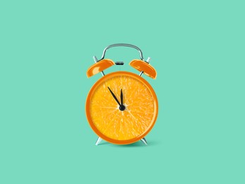 Image of Juicy orange on alarm clock dial against turquoise background. Creative poster