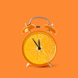 Image of Juicy orange on alarm clock dial against dark orange background. Creative poster