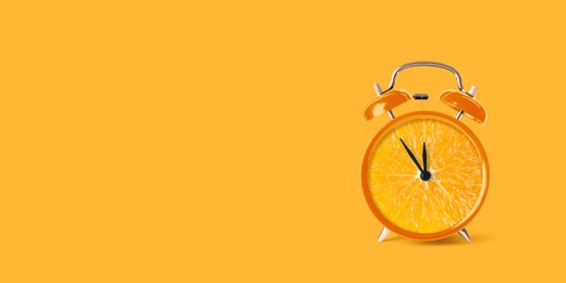 Juicy orange on alarm clock dial against orange background. Creative poster with space for text, banner design