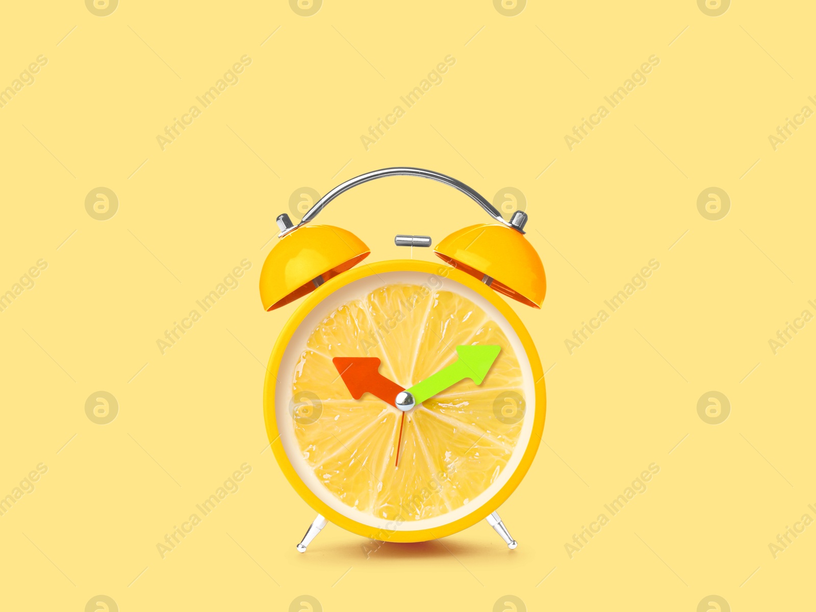 Image of Juicy lemon on alarm clock dial against light yellow background. Creative poster