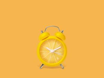 Image of Juicy lemon on alarm clock dial against orange background. Creative poster