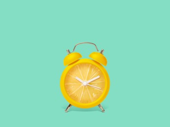 Image of Juicy lemon on alarm clock dial against turquoise background. Creative poster