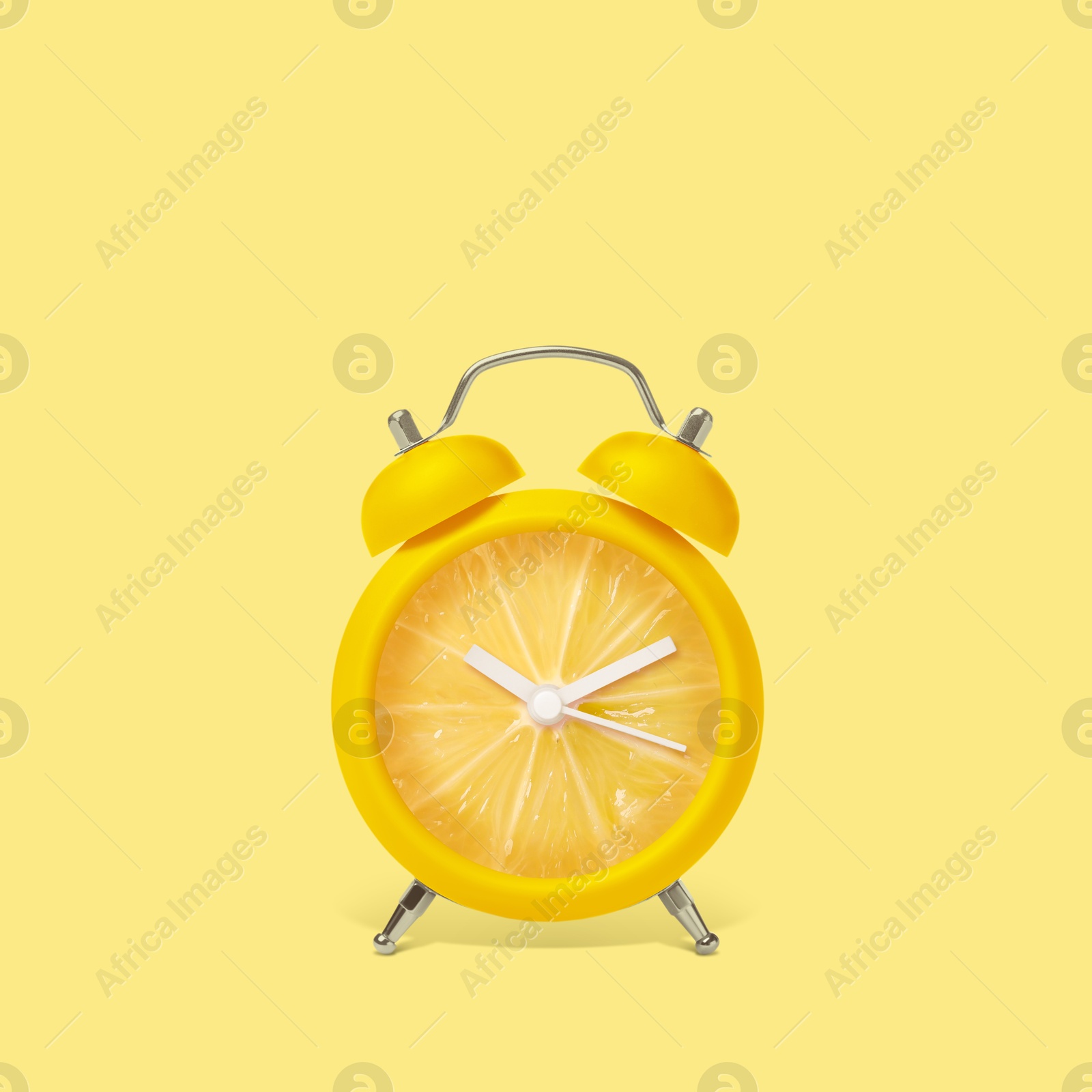 Image of Juicy lemon on alarm clock dial against light yellow background. Creative poster