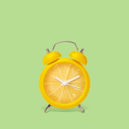 Image of Juicy lemon on alarm clock dial against light green background. Creative poster