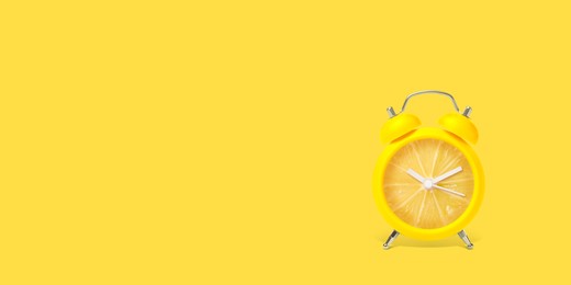 Image of Juicy lemon on alarm clock dial against yellow background. Creative poster with space for text, banner design