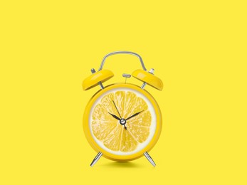 Image of Juicy lemon on alarm clock dial against yellow background. Creative poster