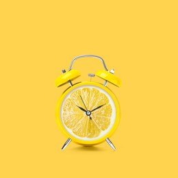 Image of Juicy lemon on alarm clock dial against yellow background. Creative poster