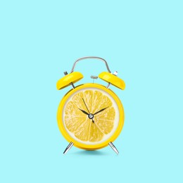 Image of Juicy lemon on alarm clock dial against light blue background. Creative poster