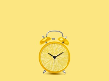 Juicy lemon on alarm clock dial against light yellow background. Creative poster