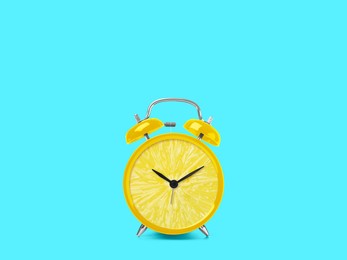 Image of Juicy lemon on alarm clock dial against light blue background. Creative poster