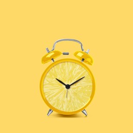 Image of Juicy lemon on alarm clock dial against light yellow background. Creative poster