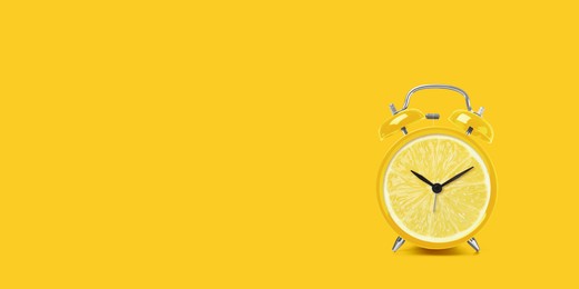 Juicy lemon on alarm clock dial against yellow background. Creative poster with space for text, banner design