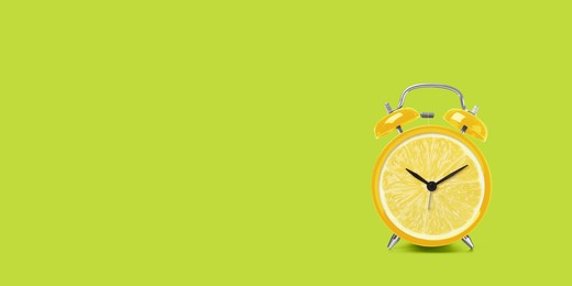 Juicy lemon on alarm clock dial against light green background. Creative poster with space for text, banner design