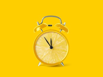 Image of Juicy lemon on alarm clock dial against yellow background. Creative poster