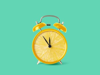 Juicy lemon on alarm clock dial against turquoise background. Creative poster