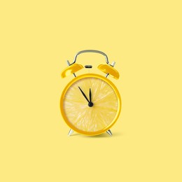 Juicy lemon on alarm clock dial against light yellow background. Creative poster