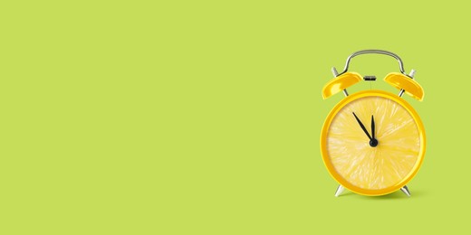 Juicy lemon on alarm clock dial against light green background. Creative poster with space for text, banner design