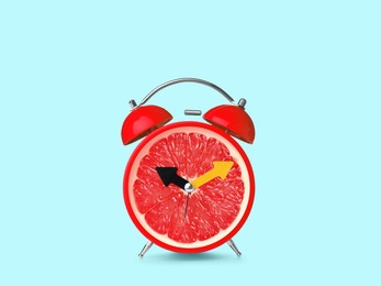 Image of Juicy grapefruit on alarm clock dial against light blue background. Creative poster