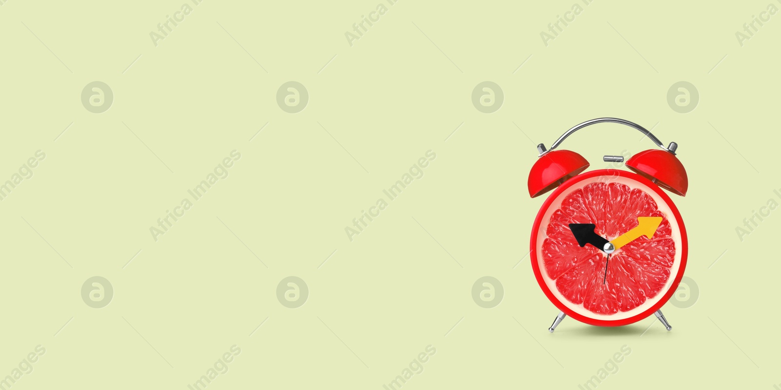 Image of Juicy grapefruit on alarm clock dial against light green background. Creative poster with space for text, banner design