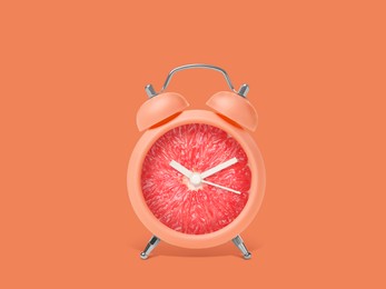 Juicy grapefruit on alarm clock dial against orange background. Creative poster