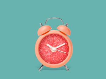 Image of Juicy grapefruit on alarm clock dial against dark turquoise background. Creative poster