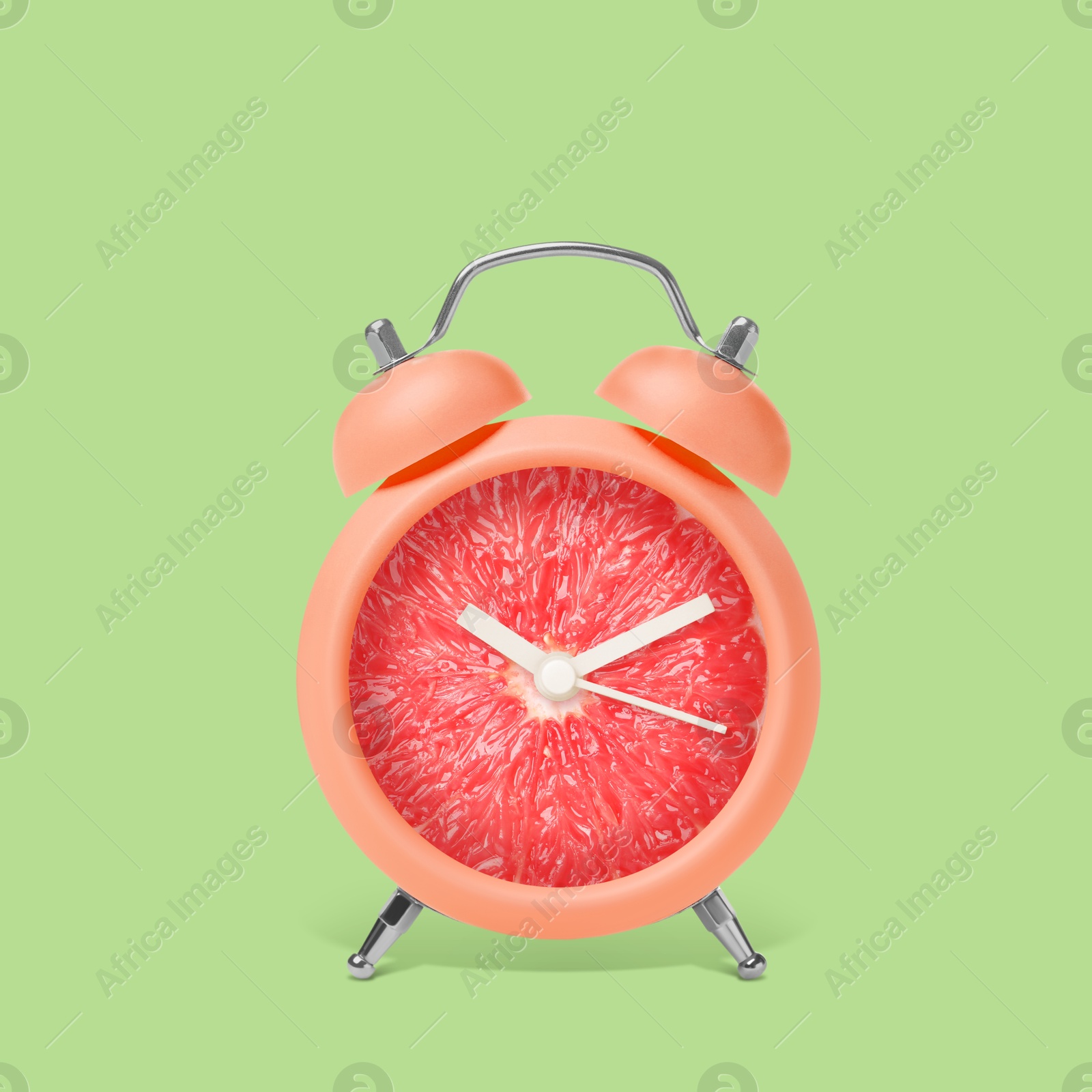 Image of Juicy grapefruit on alarm clock dial against light green background. Creative poster