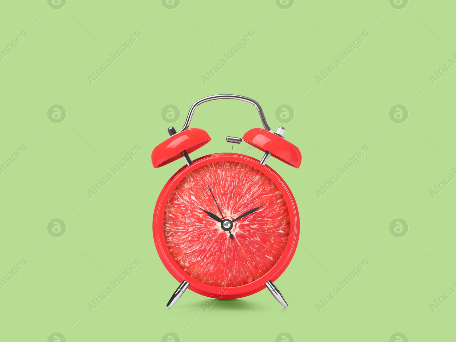 Image of Juicy grapefruit on alarm clock dial against light green background. Creative poster