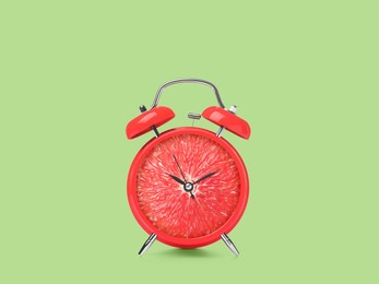 Image of Juicy grapefruit on alarm clock dial against light green background. Creative poster