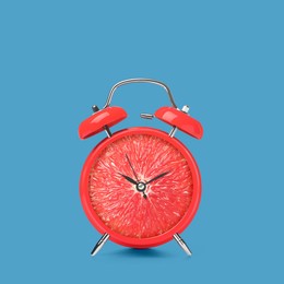 Image of Juicy grapefruit on alarm clock dial against blue background. Creative poster