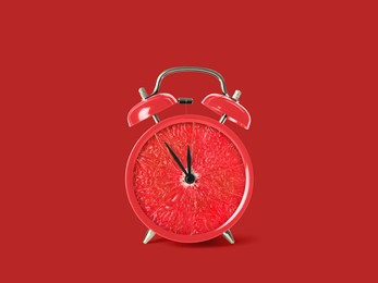 Image of Juicy grapefruit on alarm clock dial against red background. Creative poster