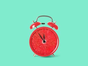 Juicy grapefruit on alarm clock dial against turquoise background. Creative poster