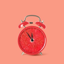 Juicy grapefruit on alarm clock dial against pink background. Creative poster