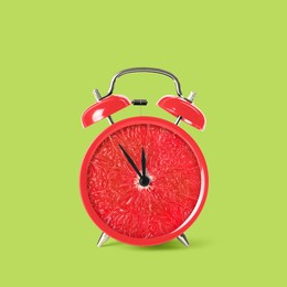 Image of Juicy grapefruit on alarm clock dial against light green background. Creative poster