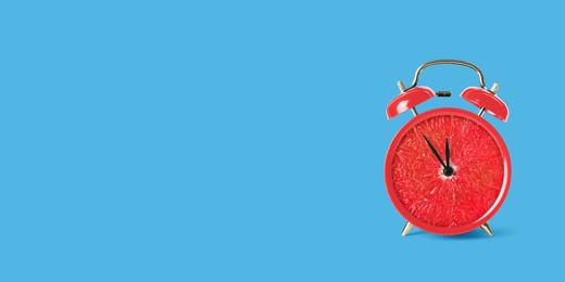 Image of Juicy grapefruit on alarm clock dial against light blue background. Creative poster with space for text, banner design