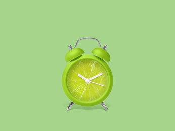 Image of Juicy lime on alarm clock dial against light green background. Creative poster