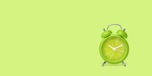 Image of Juicy lime on alarm clock dial against light green background. Creative poster with space for text, banner design