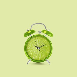 Juicy lime on alarm clock dial against light green background. Creative poster