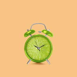 Juicy lime on alarm clock dial against light orange background. Creative poster