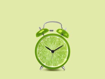 Image of Juicy lime on alarm clock dial against light green background. Creative poster