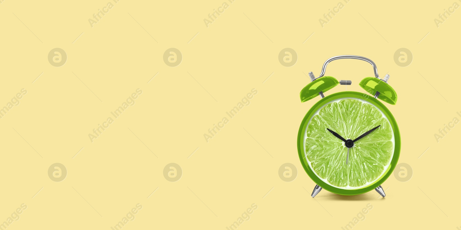 Image of Juicy lime on alarm clock dial against light orange background. Creative poster with space for text, banner design