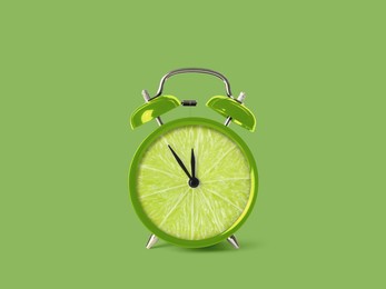 Juicy lime on alarm clock dial against light green background. Creative poster