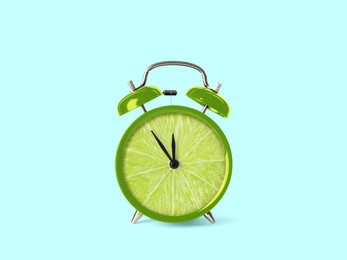 Image of Juicy lime on alarm clock dial against light blue background. Creative poster