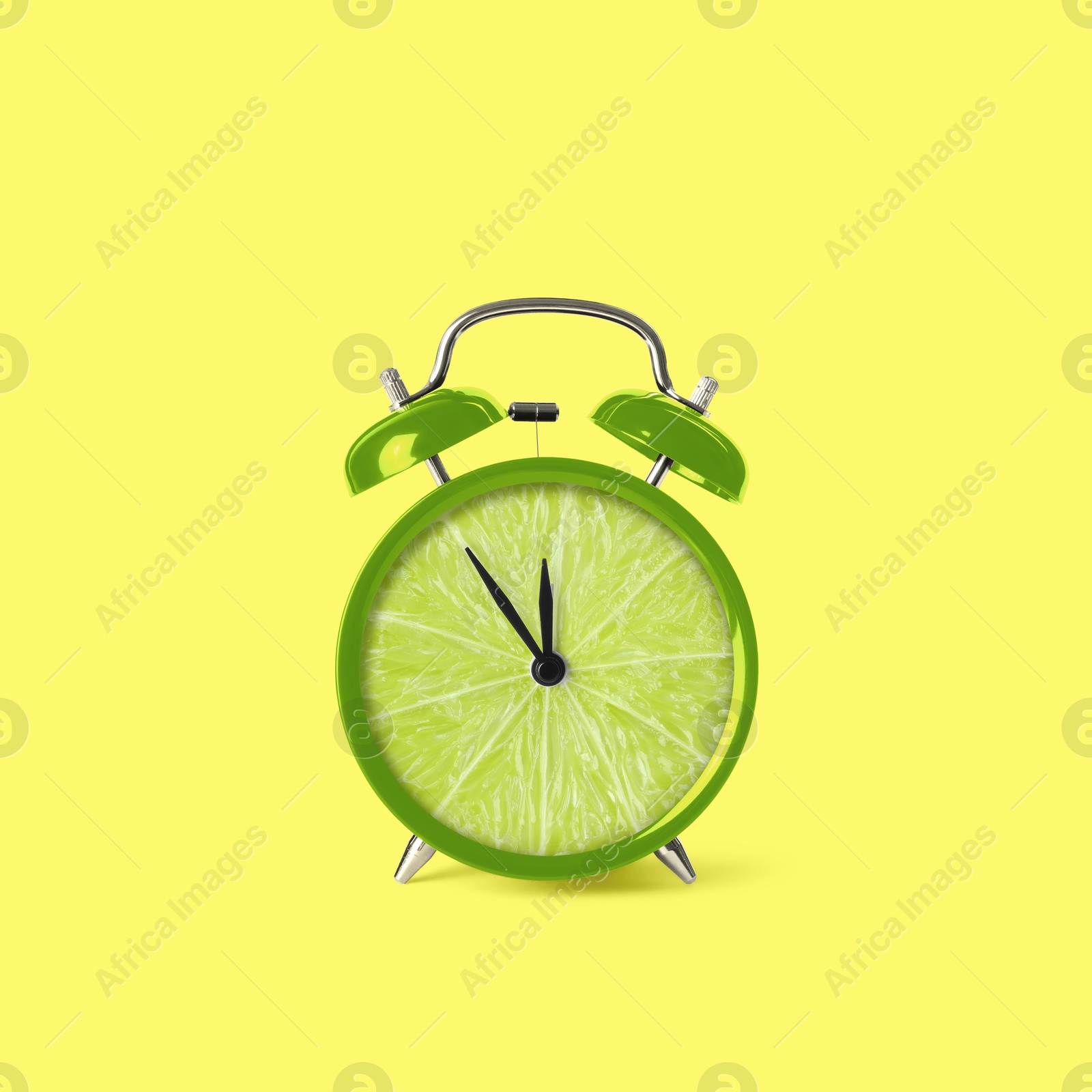 Image of Juicy lime on alarm clock dial against light yellow background. Creative poster