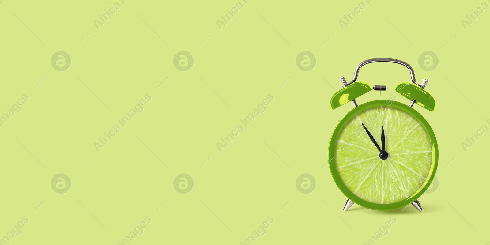 Image of Juicy lime on alarm clock dial against light green background. Creative poster with space for text, banner design