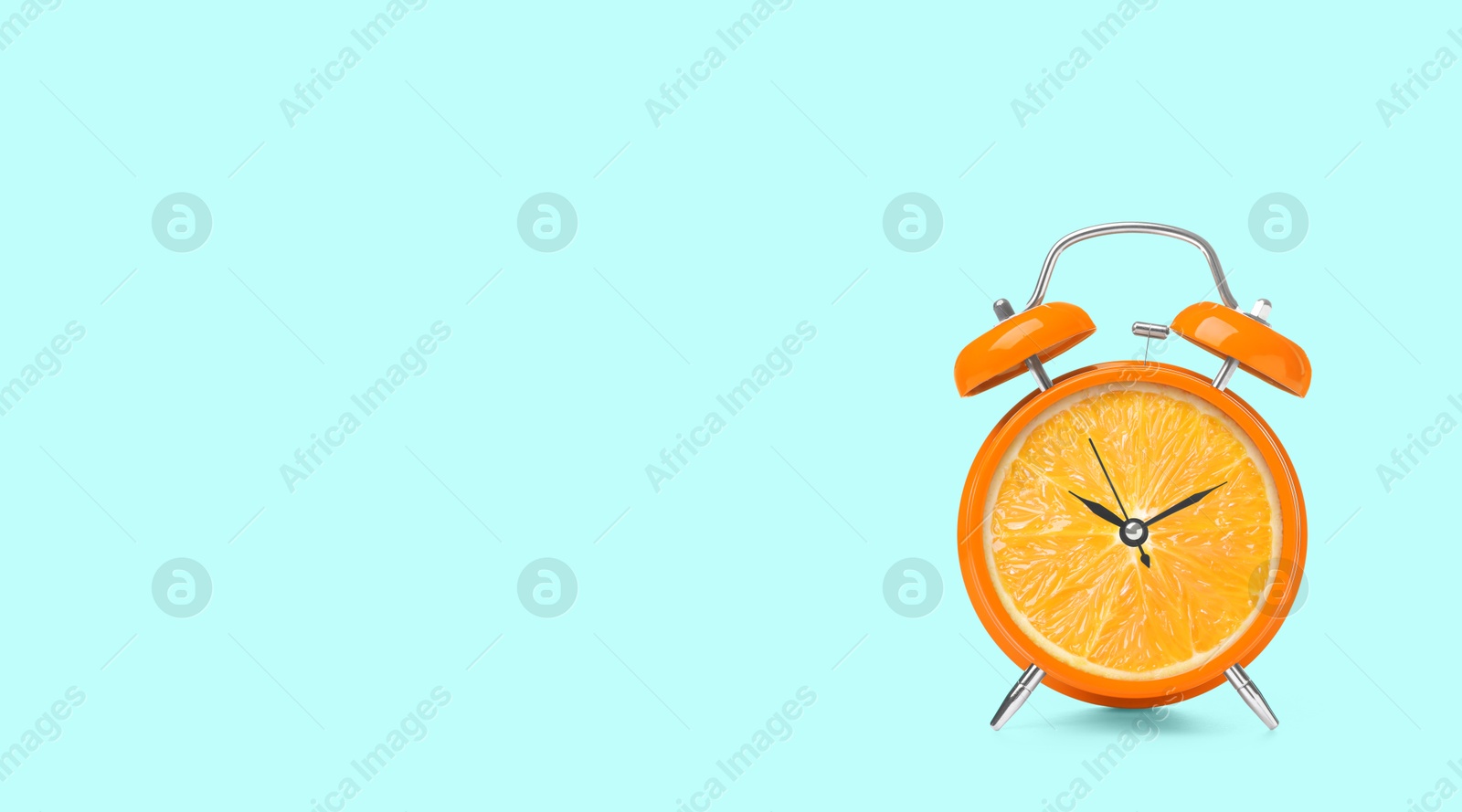 Image of Juicy orange on alarm clock dial against light blue background. Creative poster with space for text, banner design