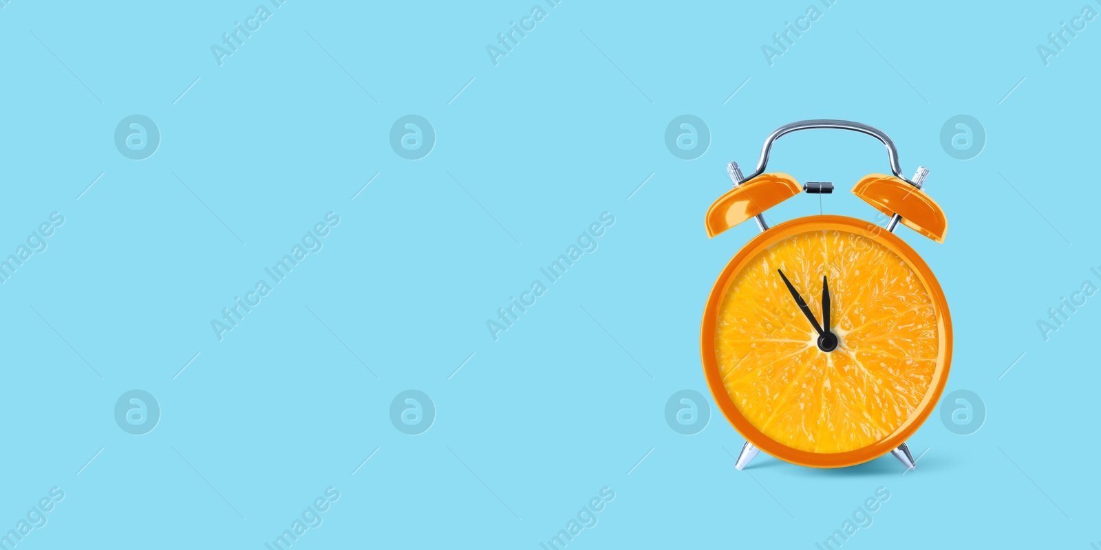 Image of Juicy orange on alarm clock dial against light blue background. Creative poster with space for text, banner design