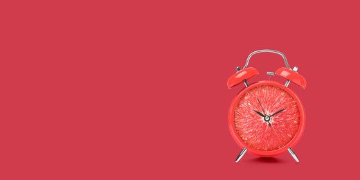 Image of Juicy grapefruit on alarm clock dial against crimson background. Creative poster with space for text, banner design